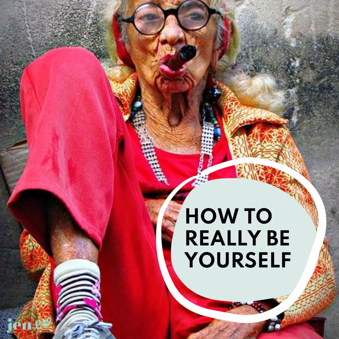 A very colorful and relaxed older woman smoking a cigar with her knee propped up and a blue circle with the words How To Really Be Yourself